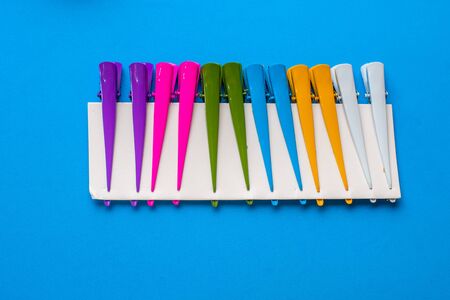 multicolored hairdressing hair clips on cardboard on a blue background cool