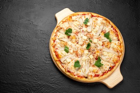 Pizza on a black background on a tomato base with mozzarella, grilled chicken, pineapples and parsley, there is a place for the inscription,Deliciousの写真素材