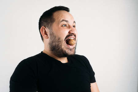 a man tries to crack a nut with his teeth. the concept of a complex problemの写真素材