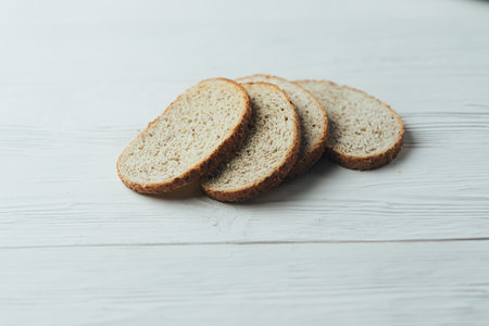 A white and silver toaster sits on a white wooden table with slices