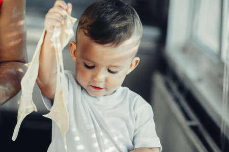 little boy with mom in the kitchen preparing flour from those of the test dish, dumplingsの写真素材