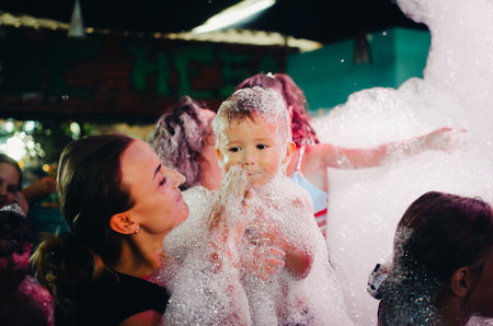 A young mother at the party with the child at a foam showの写真素材