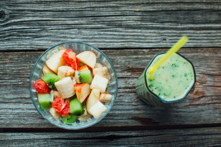 wood texture salad in a glass container with different fruits next green smoothieの写真素材