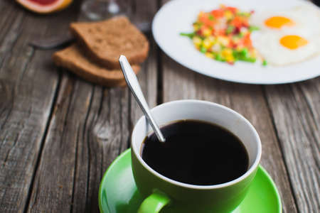 Coffee in a green mug on wooden surface