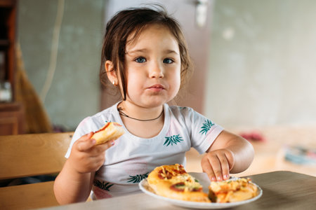 A girl, a child on the street eats a mini pizzaの写真素材