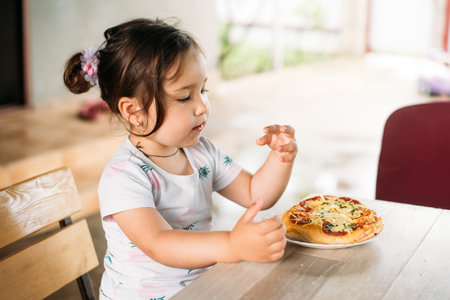 A girl, a child on the street eats a mini pizzaの写真素材
