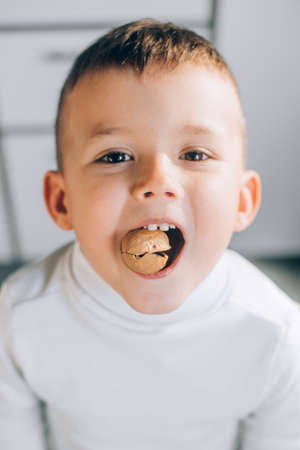 A boy child tries to crack a walnut showing healthy strong baby teeth, makes an effort