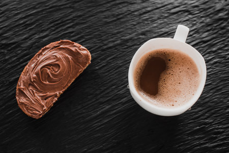 Coffee cappuccino or latte next to bread with chocolate on a black background like stone micaの写真素材