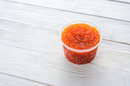 red caviar in a plastic jar on a white wooden backgroundの写真素材
