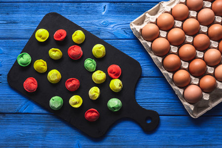 colored dumplings on a bright blue wooden background, on a black board, next to a package of raw...