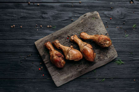 smoked homemade chicken drumstick on a wooden background and an old wooden hot smoked stickの写真素材