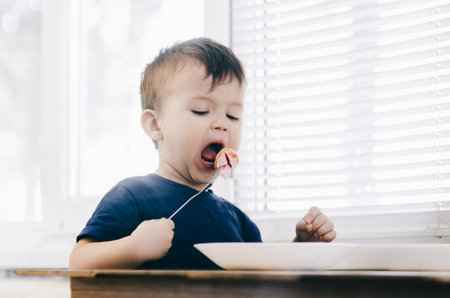 baby eating sausage in the kitchen is very charming and emotional