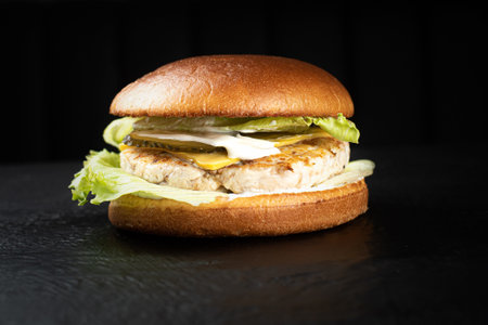 Juicy chicken hamburger on a black wooden backgroundの写真素材