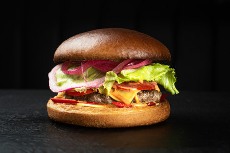 Cheeseburger with beef cutlet and cheese cheder on a black backgroundの写真素材