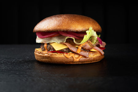 Cheeseburger with beef cutlet and cheese cheder on a black backgroundの写真素材
