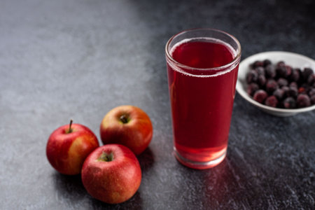 A glass of red liquid is poured into a glass next to a bowl of blueberries. Concept of relaxation...