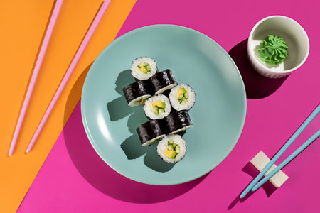 A plate of sushi with a green sauce on top. The plate is on a table with a pink backgroundの写真素材