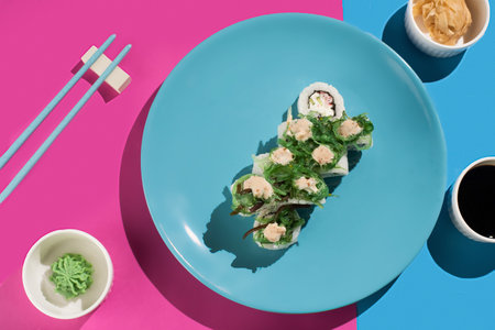 Fresh green sushi rolls filled with crab and cucumber, served on a turquoise plate with soy sauce and wasabiの写真素材