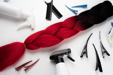 Kanekalon two- color-artificial hair Ombre red and black for braiding braids, lying on a white background next to accessoriesの写真素材