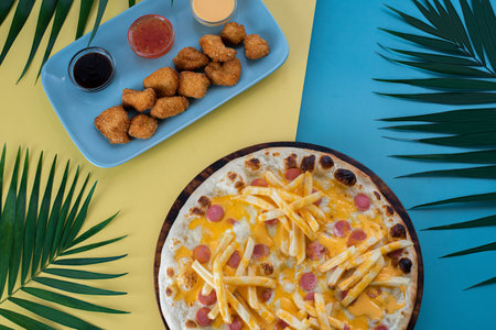 A creative kids' meal with fries pizza, nuggets, and sauces on a vibrant, playful backgroundの写真素材