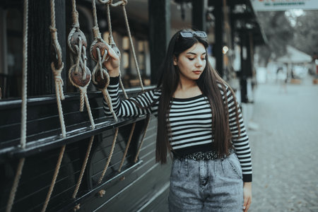 Stylish woman in a striped shirt standing confidently in an urban environment.の写真素材
