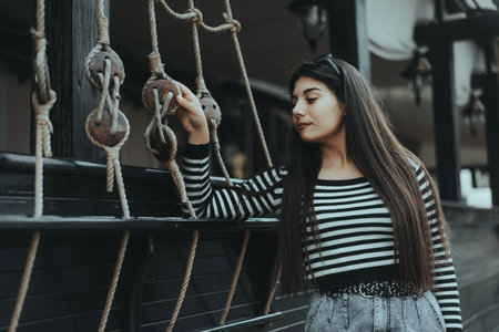 Casual woman posing near a stone wall, representing independence and urban life.の写真素材
