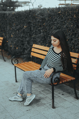 A stylish woman relaxing against a fence in the middle of a busy day.の写真素材