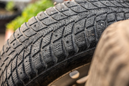 A detailed close-up of a used tire tread, showing signs of wear, ideal for automotive or...