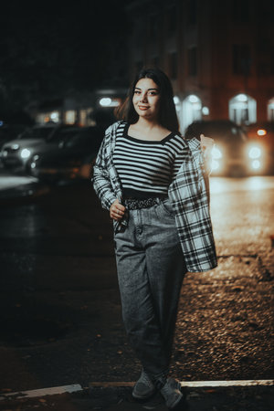 A stylish brunette poses confidently in the middle of the city at night, exuding attitude and style...