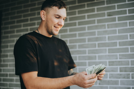 A young man outdoors lifting a large car tire, showing strength and hard work in a casual setting.の写真素材