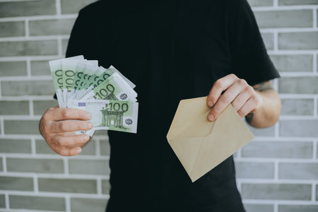 Man placing euro notes into an envelope, symbolizing financial savings and budgeting strategies.の写真素材