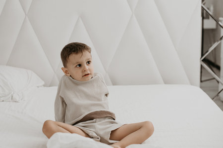 Little boy sitting on bed, feet in focus, cozy atmosphereの写真素材