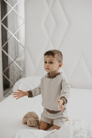 Little boy lying on bed with bear, feet in focus, cozy atmosphereの写真素材