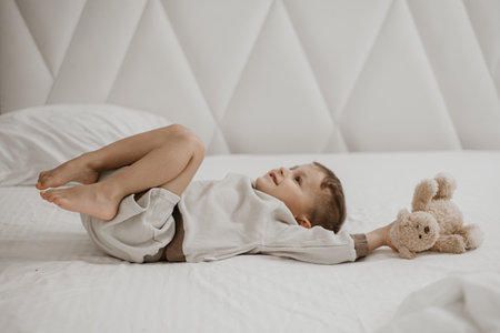 Little boy lying on bed with arms stretched, playful and carefree.の写真素材