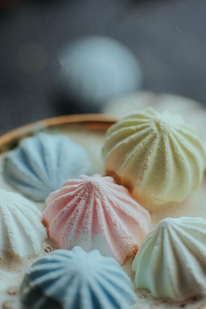 A luxurious golden-handled cup filled with hot coffee and topped with colorful pastel meringues. The elegant composition blends warmth and sweetness in a cozy aesthetic.の写真素材