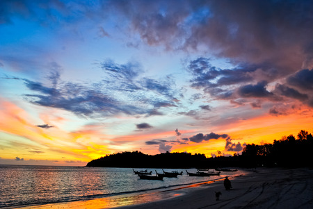 Silhouette boats on the beach against the colorful sunsetの写真素材