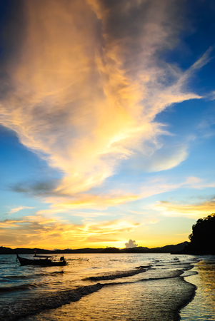 Silhouette Sun Set Behind The Sea Shore With The Orange Cloud on The Blue Skyの写真素材