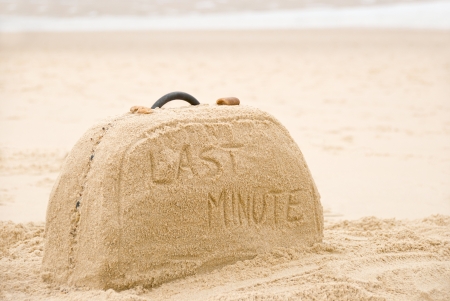 Last minute written on suitcase build out of sand on beach conceptの写真素材