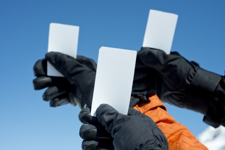 Gloved hands holding lift pass against blue sky. Concept to illustrate ski admission feeの写真素材