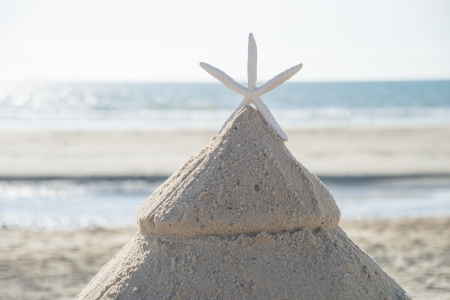 Christmas on beach tree made out of sand with starfish as top decoration. Concept for escaping the...