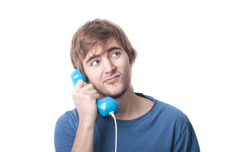 Blonde young male on telephone looking at imaginary information text of communications contract. Copyspaceの写真素材