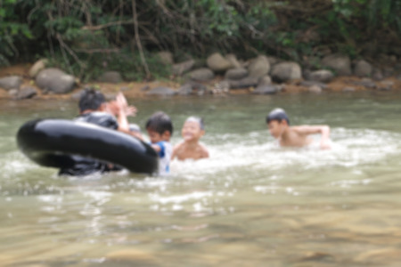 Blurry image of children swimming in river bankの写真素材