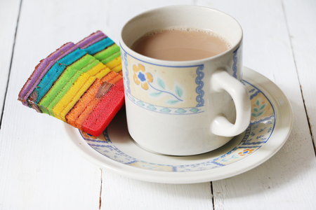 Colourful layer cake or Kek Batik Sarawak served with cup of milk teaの写真素材