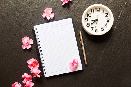 Flat lay of blank note pad, pen, clock and cherry blossom flower.の写真素材