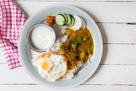 Rice served with fried egg, dal soup, fresh vegetable and yogurtの写真素材