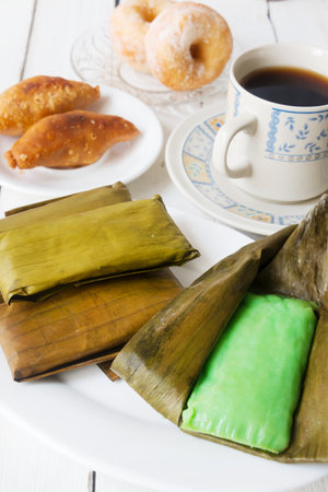 Malaysian traditional dessert 'Kuih Muih' served with coffee on white wooden tableの写真素材