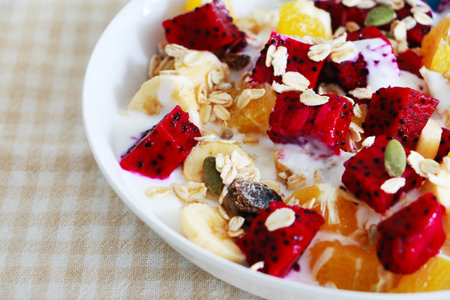 Fresh fruit salad with yogurt and muesli in a white plateの写真素材