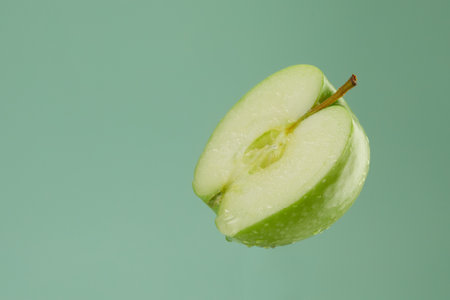 half a green apple with water drops on a green background. fresh fruit close-up. High quality 4k footageの写真素材