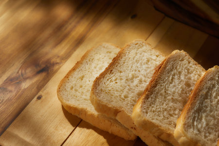 bread on the table. pieces of bread lie on a wooden board. spots of light on fresh baked goods. morning sun shines on food. High quality 4k footageの写真素材