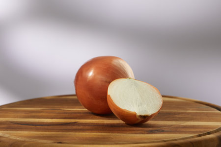 onions on a wooden cutting board. half an onion with whole ones on a gray background. vegetables ready for cutting close-up. kitchen on a sunny day. High quality 4k footageの写真素材